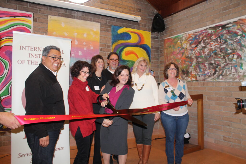 Group photo, ribbon cutting with large scissors.