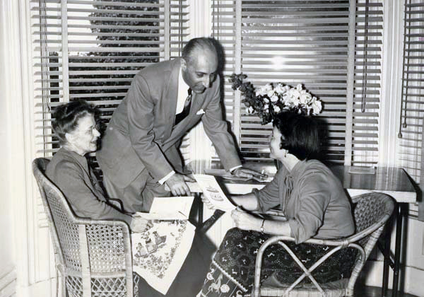 3 people, probably Annie, around a small table near a window.
