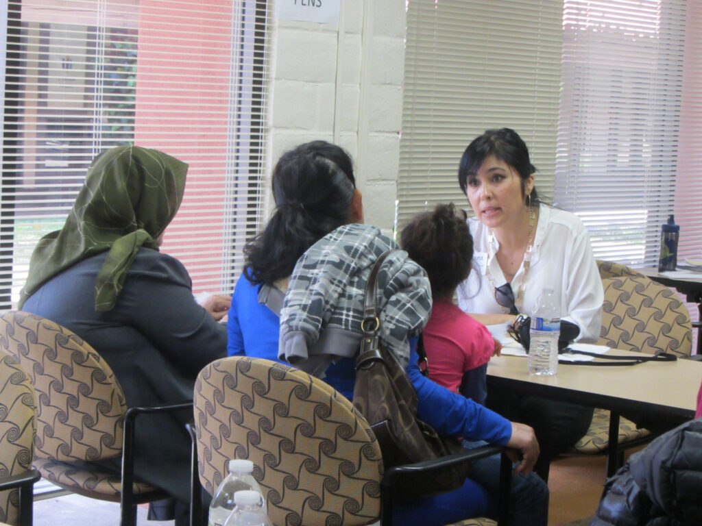 4 women + child sitting discussing at table.