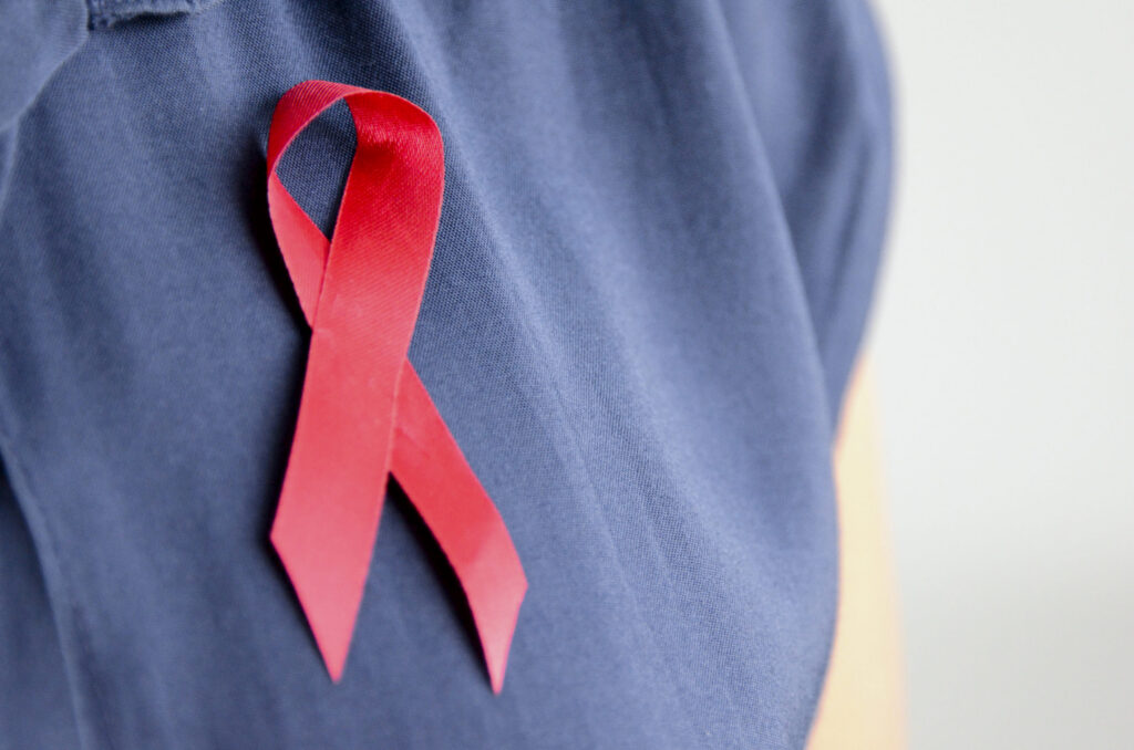 Traditional red AIDS ribbon badge on shirt close up.